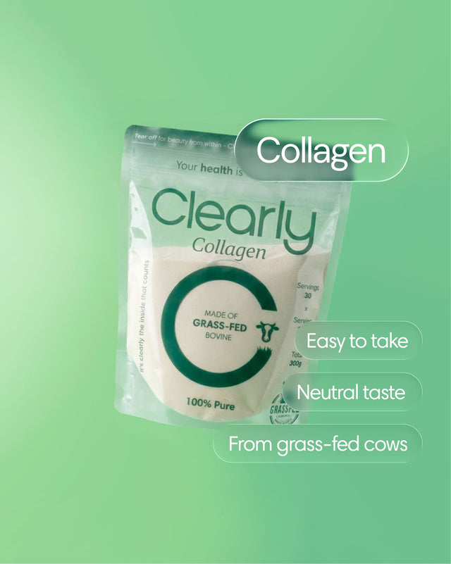 Clearly grass-fed collagen powder in a clear container with a scoop on a wooden table.