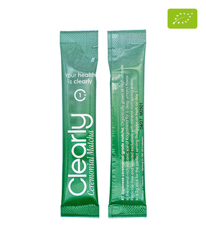 Organic matcha powder in a vibrant green color, packaged by Clearly, displayed in a small bowl on a wooden surface.